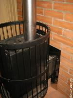 Банная печь Harvia Legend со стороны парной. Топка выведена в стену. Подключена к дымоходу из нержавеющей стали